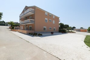 A multi-story residential building with a balcony on the second floor, a driveway, and a well-maintained lawn. - Apartments with Shared Pool Rocco 1 (Medulin)