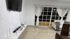 Una sala de estar moderna con un televisor de pantalla plana, una consola blanca, un sofá y una silla de madera.
