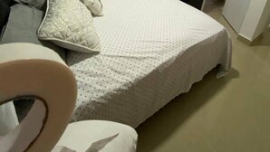 Un dormitorio con una cama, un escritorio, una silla, un televisor y un equipo de aire acondicionado.