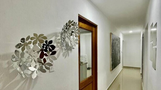 Un pasillo con puerta de madera, un adorno en la pared y suelo de baldosas.