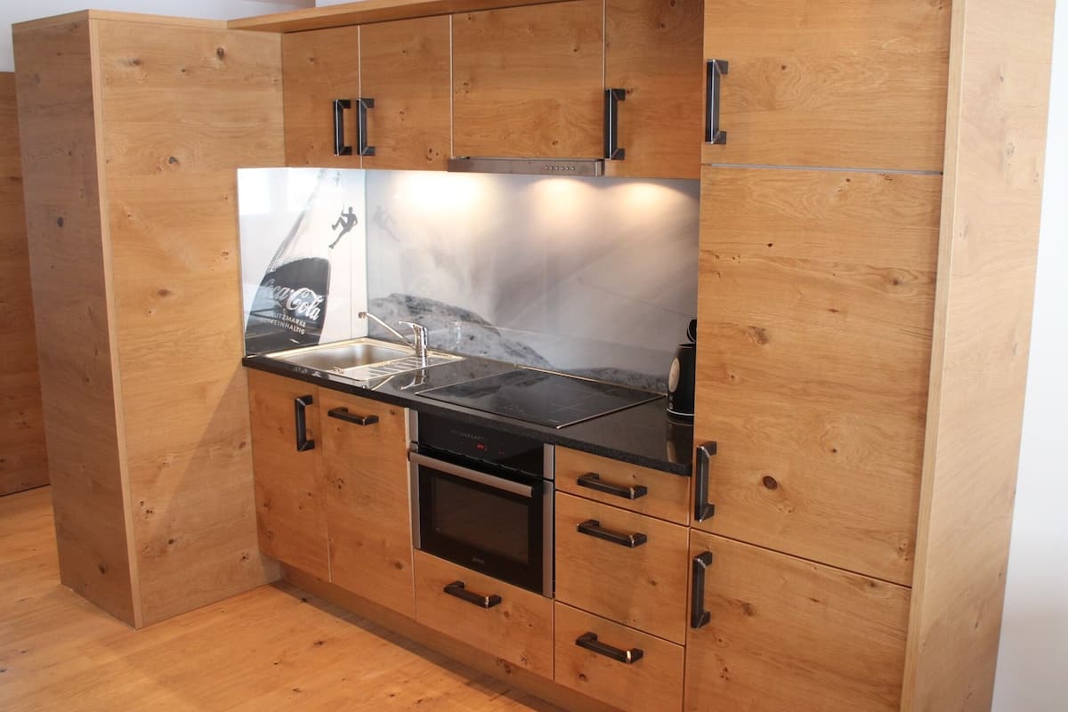 Una cocina con armarios de madera, encimera negra, electrodomésticos de acero inoxidable y salpicadero de mármol.