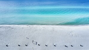 En strand med kristallklart, turkosfärgat vatten och vit sand.