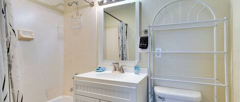 A bathroom with a bathtub, a sink, a toilet, and a mirror with lights.