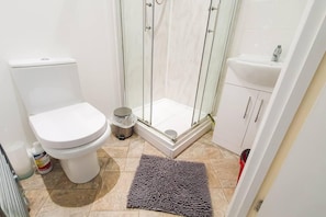 A bathroom with a toilet, a shower enclosure, a sink, and a rug. - Impeccable 4-bed House in Cheltenham (Cheltenham)