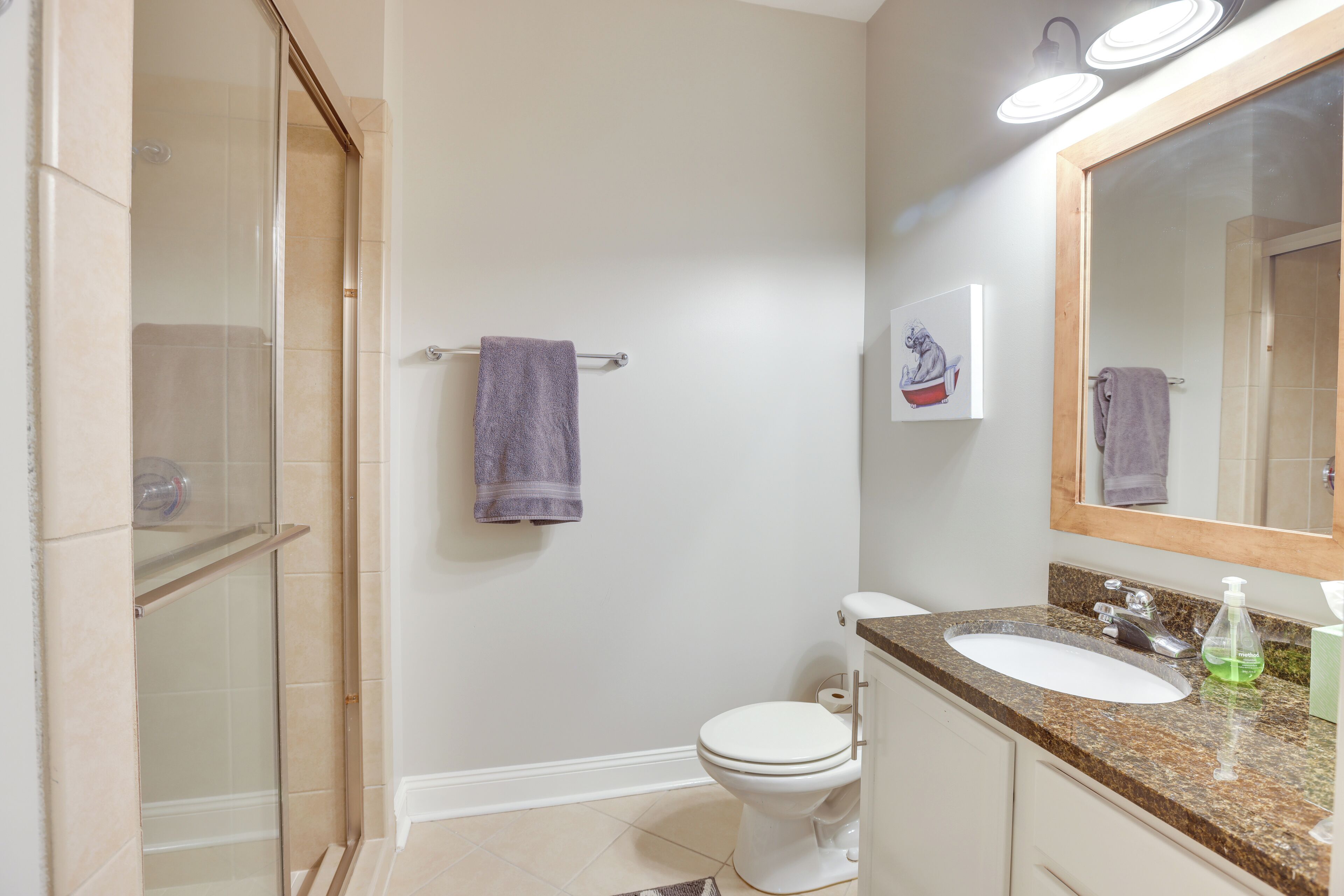 A bathroom with a shower, toilet, sink, and a mirror.