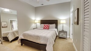 A bedroom with a bed, two bedside tables with lamps, a ceiling fan, and a large mirror. - Tuscaloosa Condo: Steps to Bryant-denny Stadium! (Tuscaloosa)