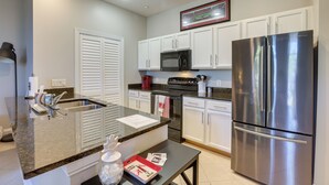 A modern kitchen with white cabinets, stainless steel appliances, and a granite countertop. - Tuscaloosa Condo: Steps to Bryant-denny Stadium! (Tuscaloosa)