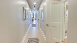 A hallway with a tiled floor, framed pictures on the walls, and a door on the right. - Tuscaloosa Condo: Steps to Bryant-denny Stadium! (Tuscaloosa)
