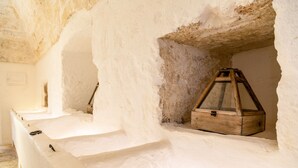 A room with a stone wall, a wooden chest, and a lantern. - Masseria Scaledda (Manduria)