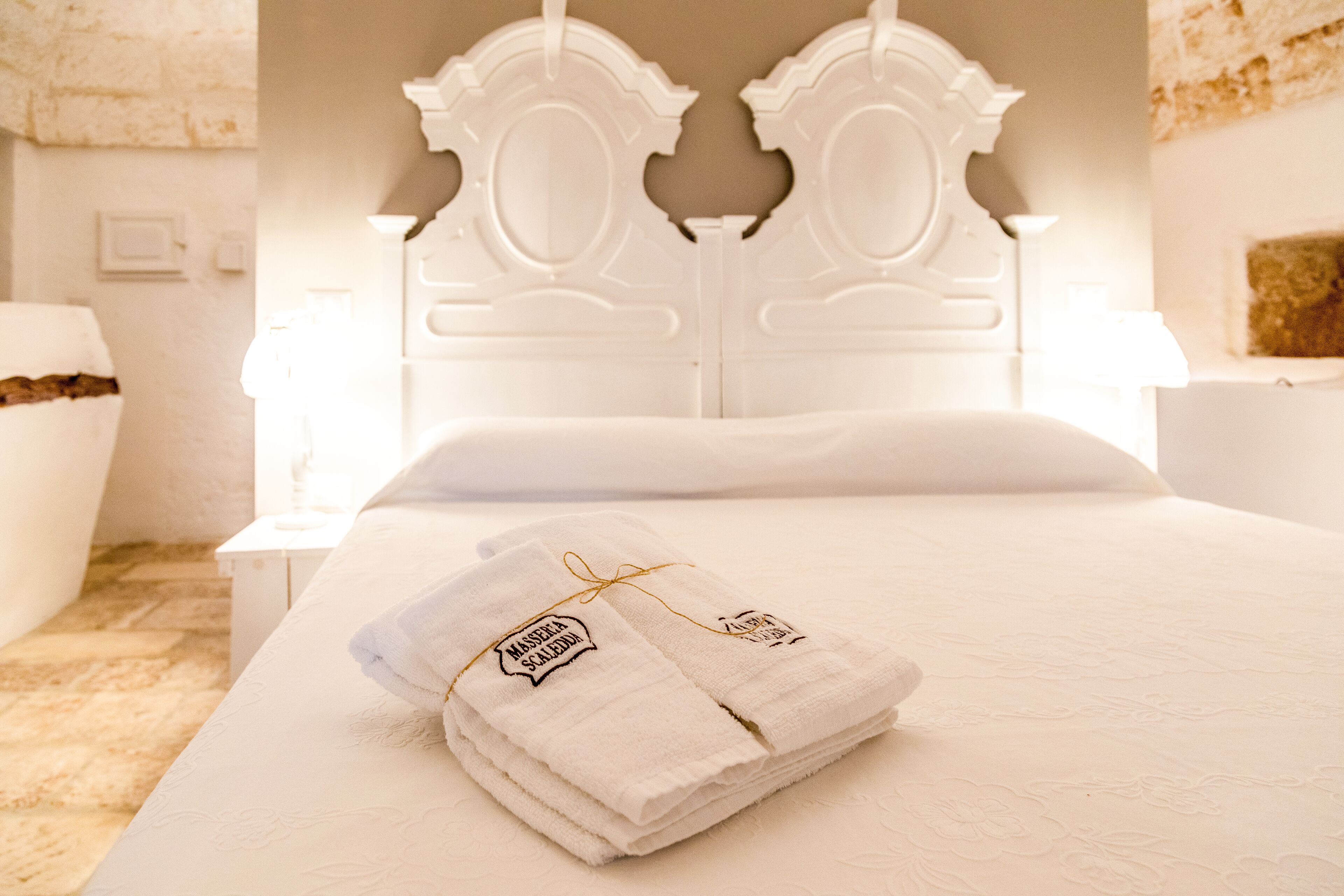 A neatly made bed with folded towels and a headboard with a decorative design.