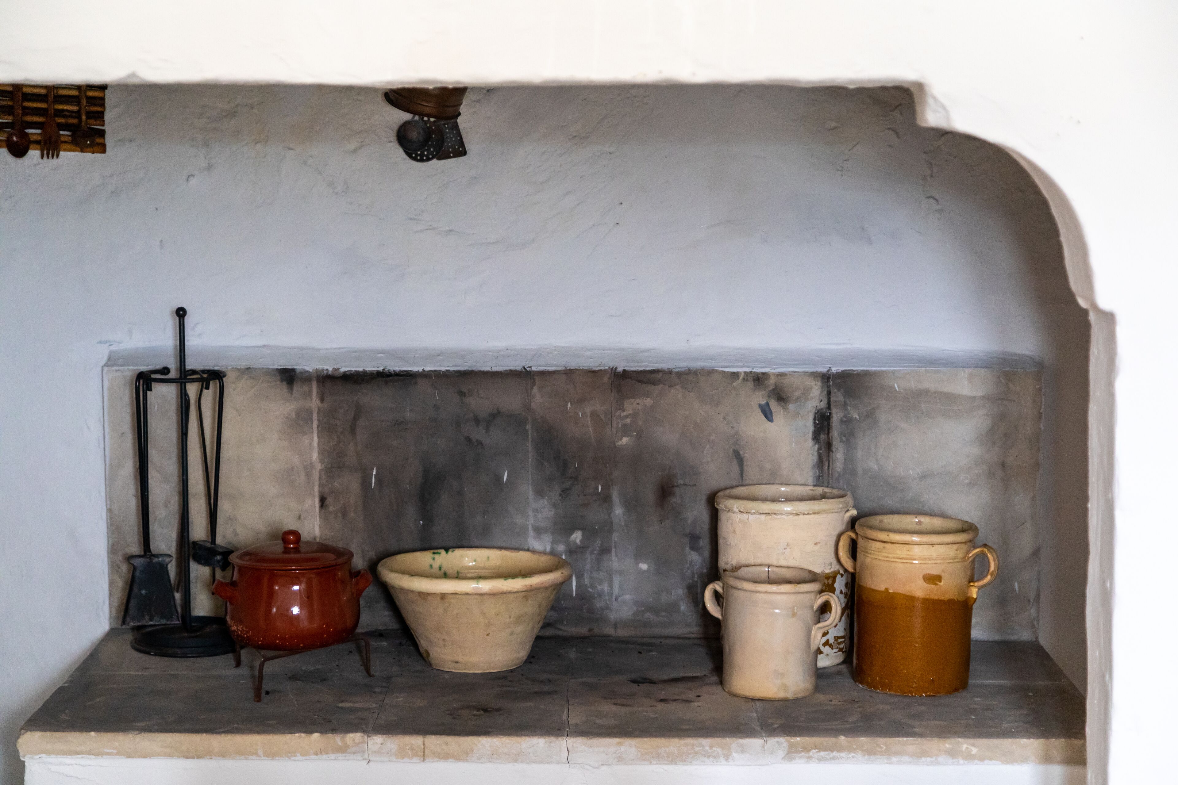 A kitchen shelf with various ceramic containers and a red pot.