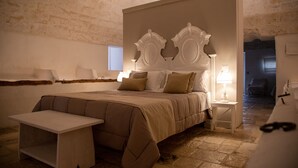 A bedroom with a large bed, a bedside table, a small table, and a lamp. - Masseria Scaledda (Manduria)