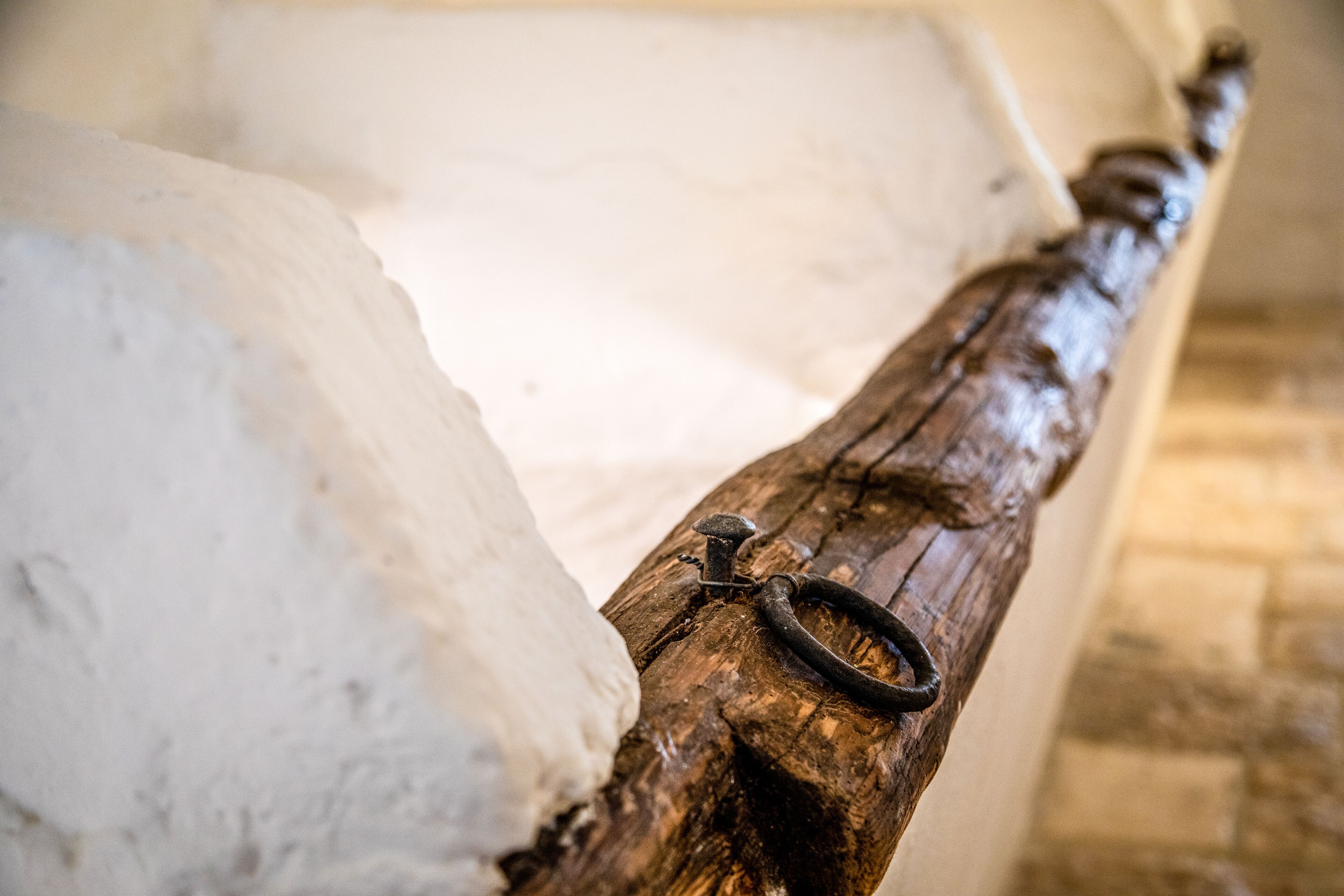 A rustic wooden bench with a metal ring, set against a stone wall.