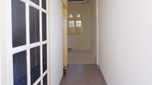 Un couloir étroit, avec une porte à gauche et une fenêtre à droite.