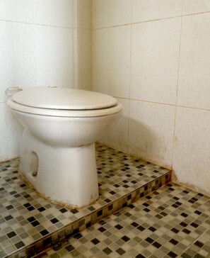 A toilet in a bathroom with a tiled floor and walls. - OYO Life 92632 Kost Pondok Kito (Jambi)