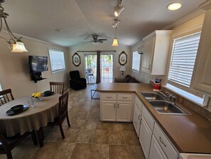 A kitchen with a dining area, a TV mounted on the wall, and a ceiling fan. - DISNEY KISSIMMEE ORLANDO FURNISHED RENTAL NIGHTLY WEEKLY MONTHLY ANNUALLY 2732 (Kissimmee)