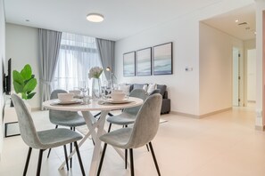 Un soggiorno moderno con zona pranzo, caratterizzato da un tavolo rotondo con sedie, un divano e un'ampia finestra con tende.
