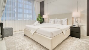 Un dormitorio de hotel moderno con una cama grande, mesitas de noche y una planta en maceta.