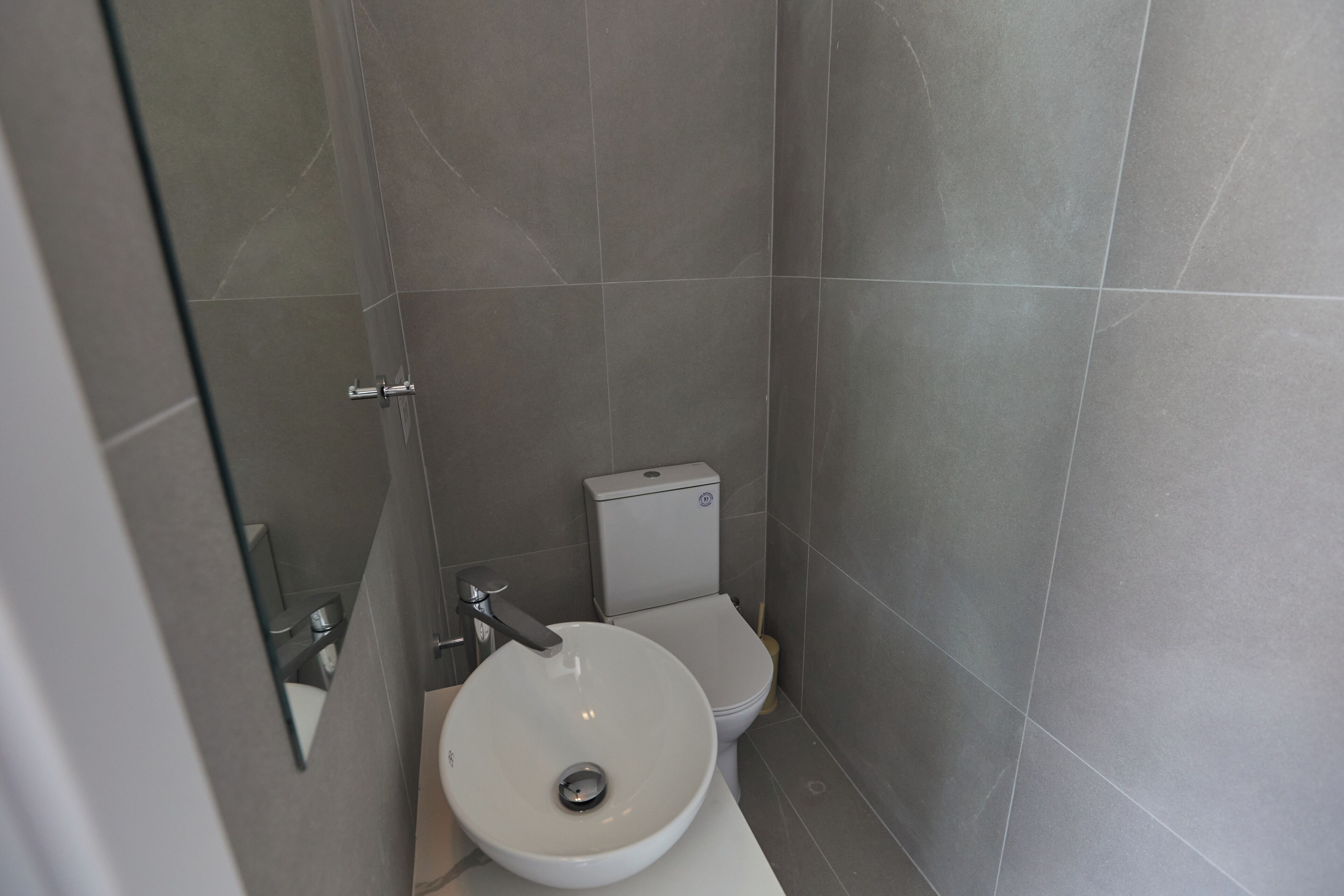 A modern bathroom with a white sink, toilet, and a glass shower enclosure.