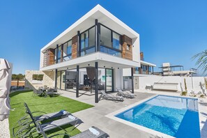 A modern two-story house with a pool, outdoor seating, and a stone wall. - Protaras Elite Pearl Villa Ep4b (Paralimni)