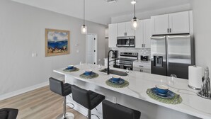 A modern kitchen with white cabinets, stainless steel appliances, and a central island with bar stools.