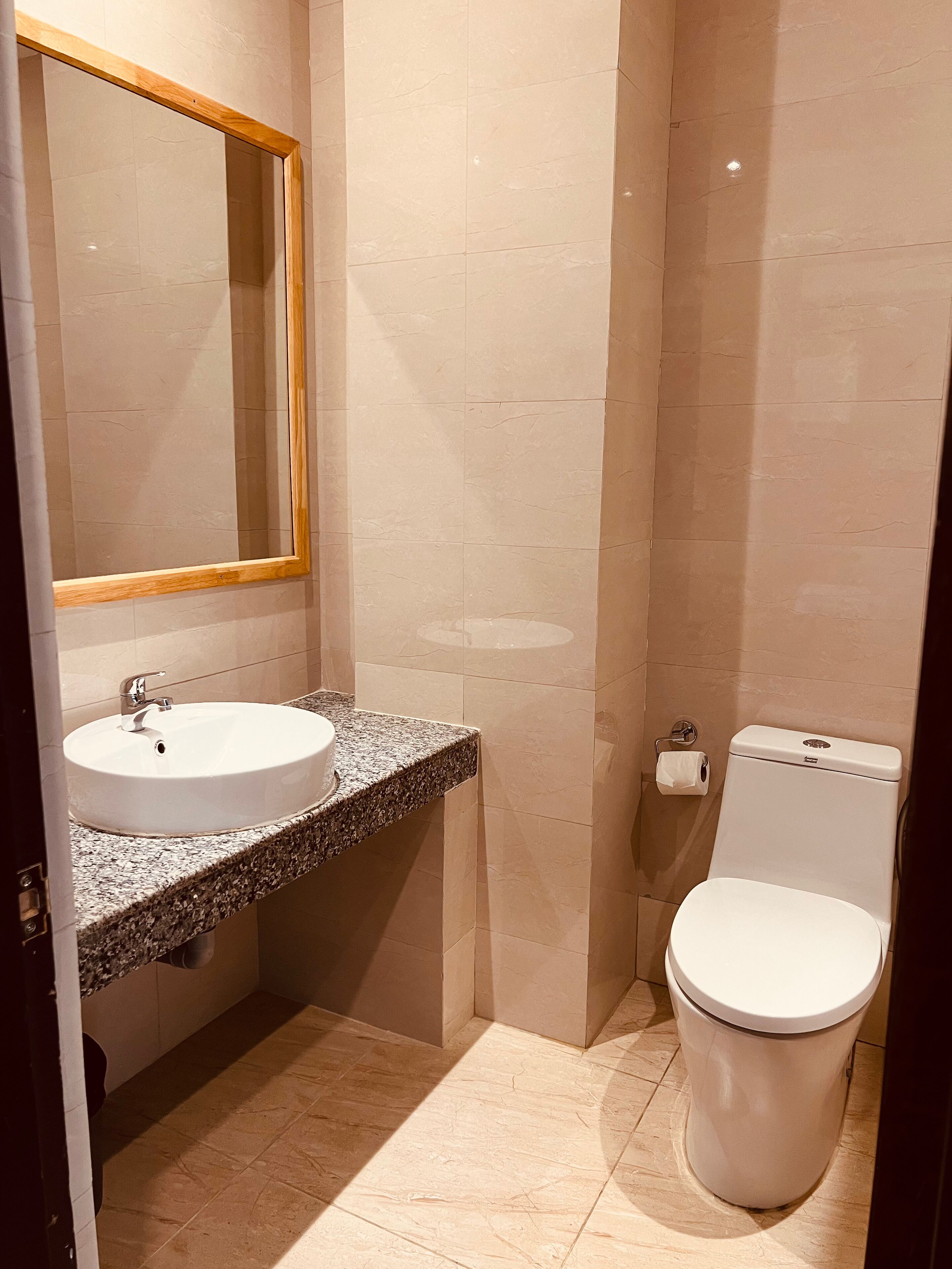 Une salle de bain avec un lavabo, un miroir, des toilettes et des murs carrelés.