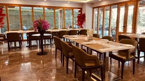 A spacious dining area with marble flooring, large windows, and modern furniture. - Hotel Mayto (Thimphu)