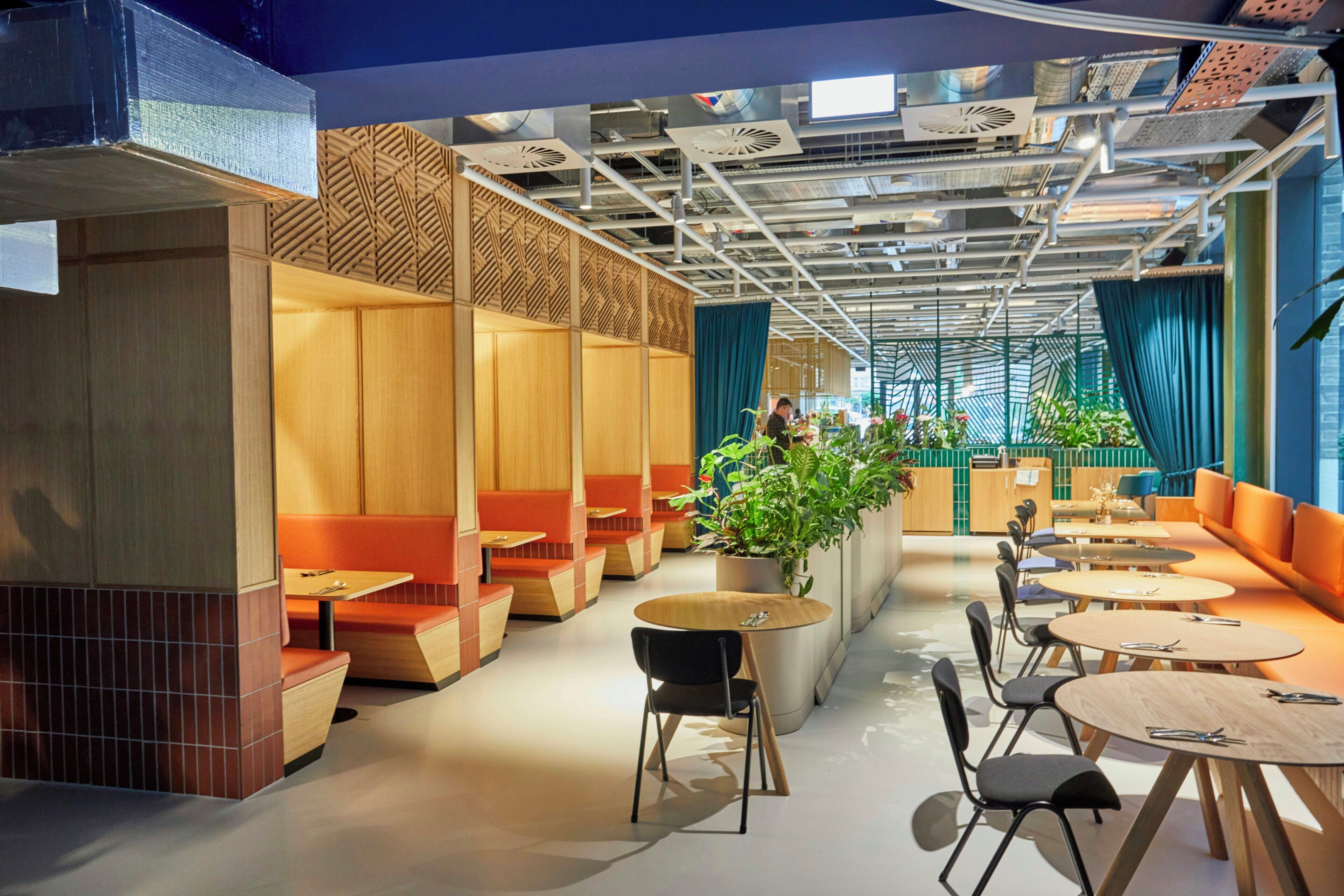 Un intérieur moderne avec des coins salon, des tables et une grande plante.