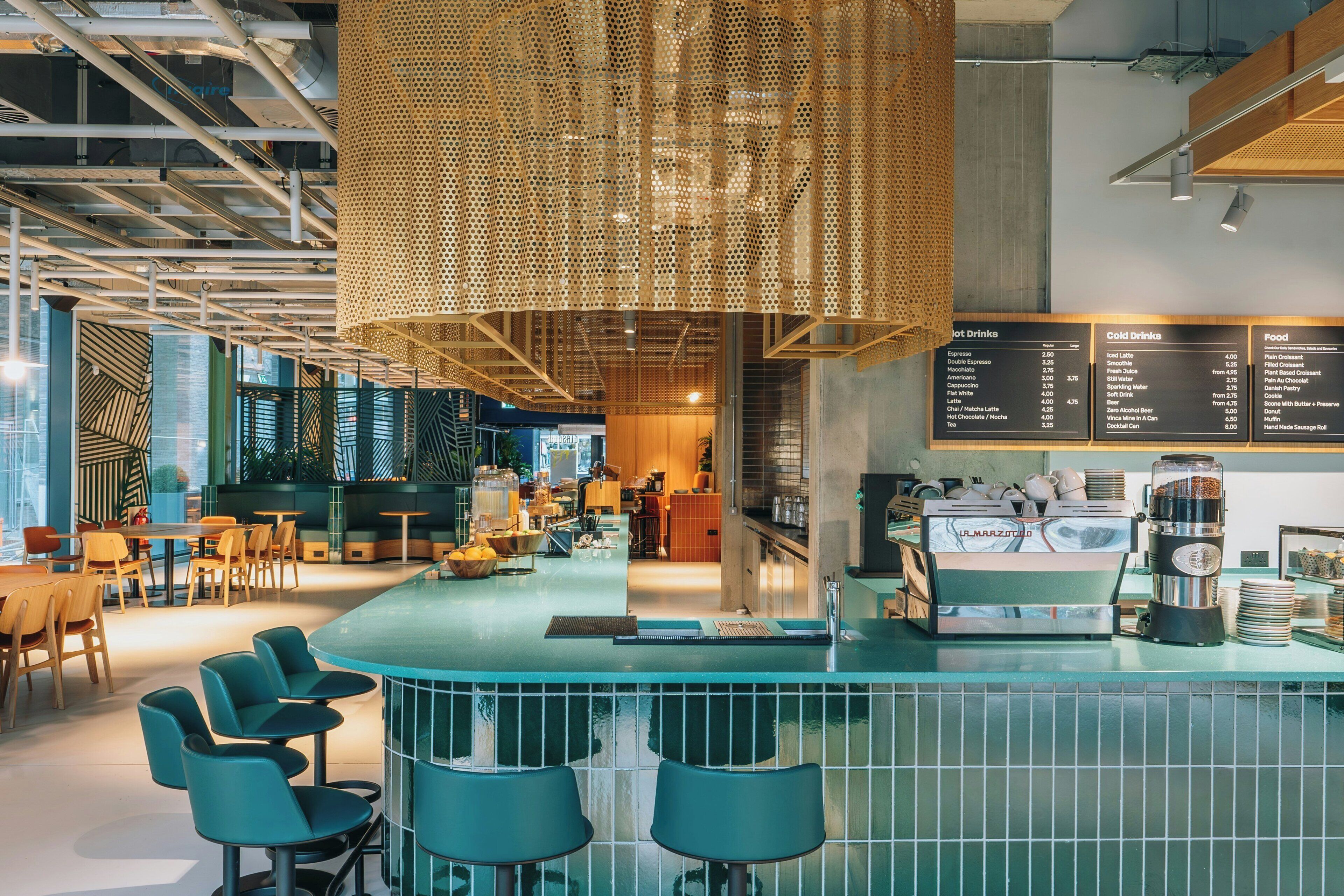 A modern bar area with seating, a menu board, and coffee machines.