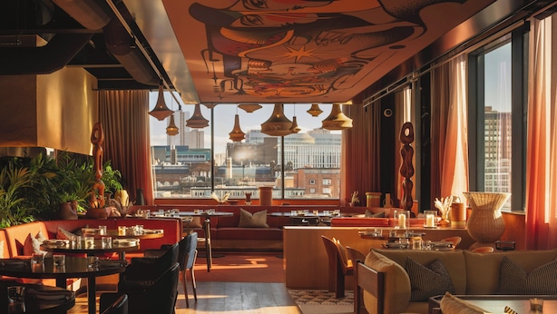 A modern interior with a city view, dining area, and seating arrangements.