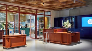 A modern interior with a wooden ceiling, a reception desk, and a large window.