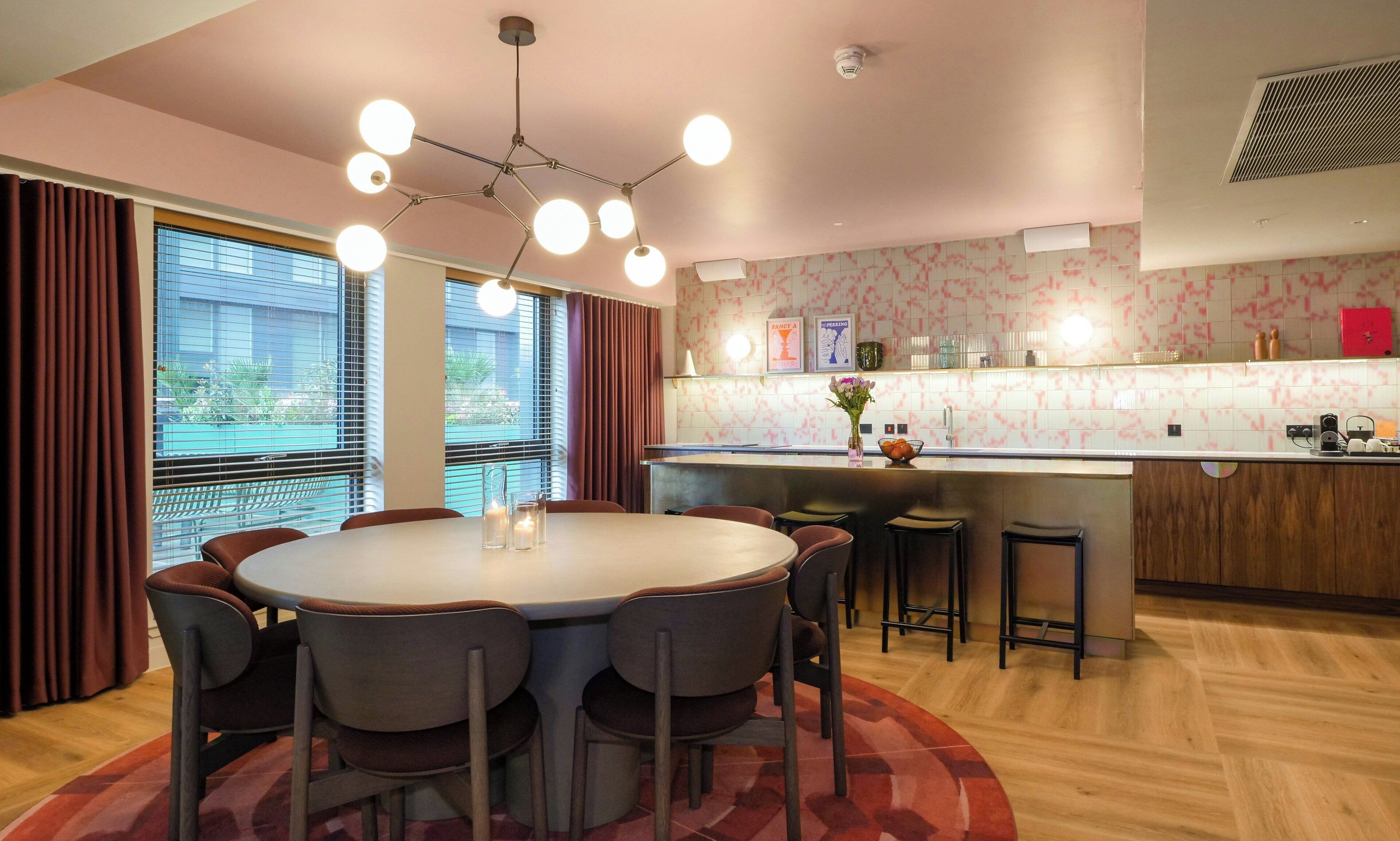 Une cuisine moderne avec une table à manger ronde, des tabourets de bar et un luminaire suspendu.