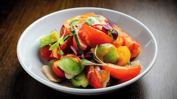 A white bowl filled with a colorful vegetable salad on a wooden table.