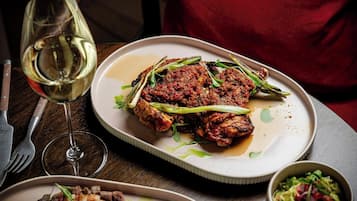 A dining table with plates of food, a wine glass, and cutlery.