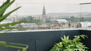 A rooftop terrace with a view of a cityscape, including a prominent clock tower.