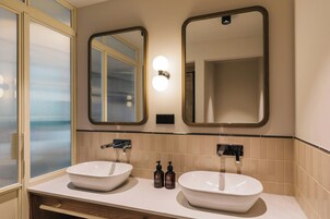 Un baño con dos lavamanos, un espejo y un ventanal con vidrio esmerilado.