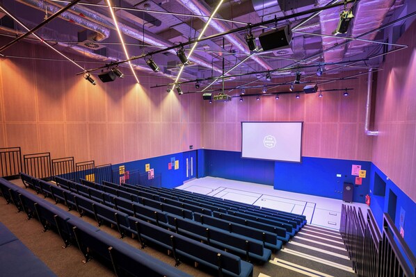 An auditorium with rows of seats, a stage, and a projection screen. - The Social Hub Glasgow (Glasgow)