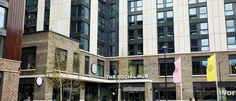 A modern building with 'The Social Hub' sign, large windows, and outdoor seating areas.