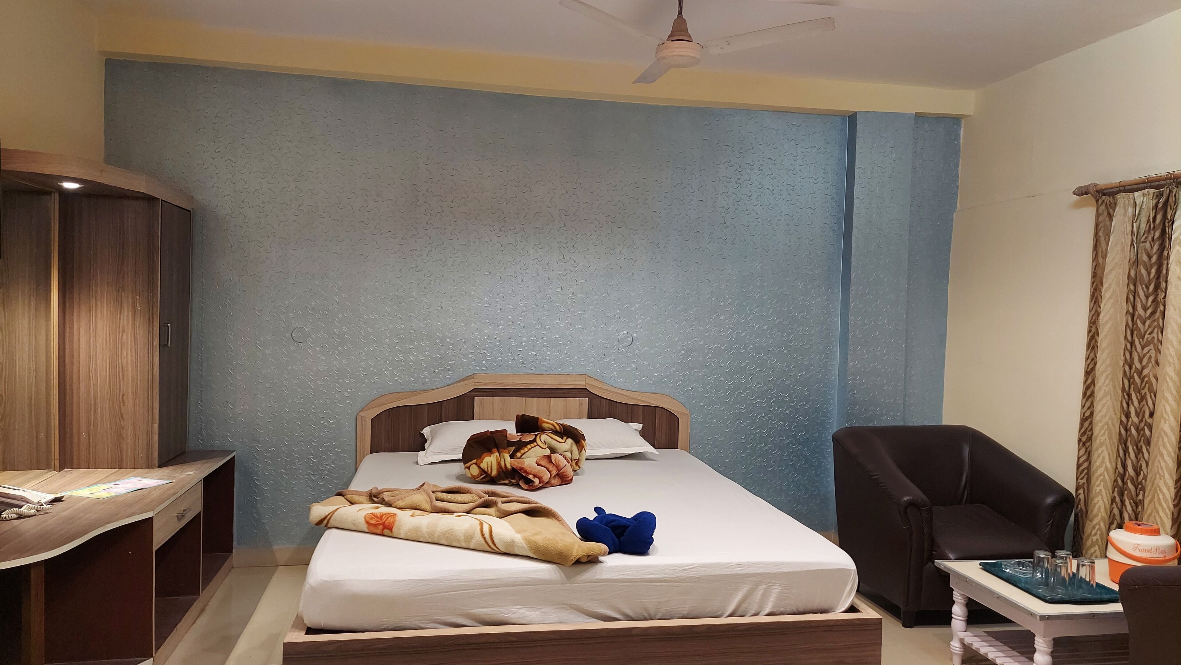 A bedroom with a wooden bed, a desk, a chair, and a ceiling fan.