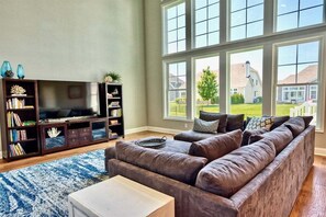 Ein Wohnzimmer mit großem Fenster, Fernseher und Bücherregal.