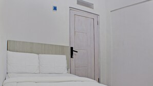 Una habitación de hotel con una cama, una puerta y un interruptor de luz en la pared.