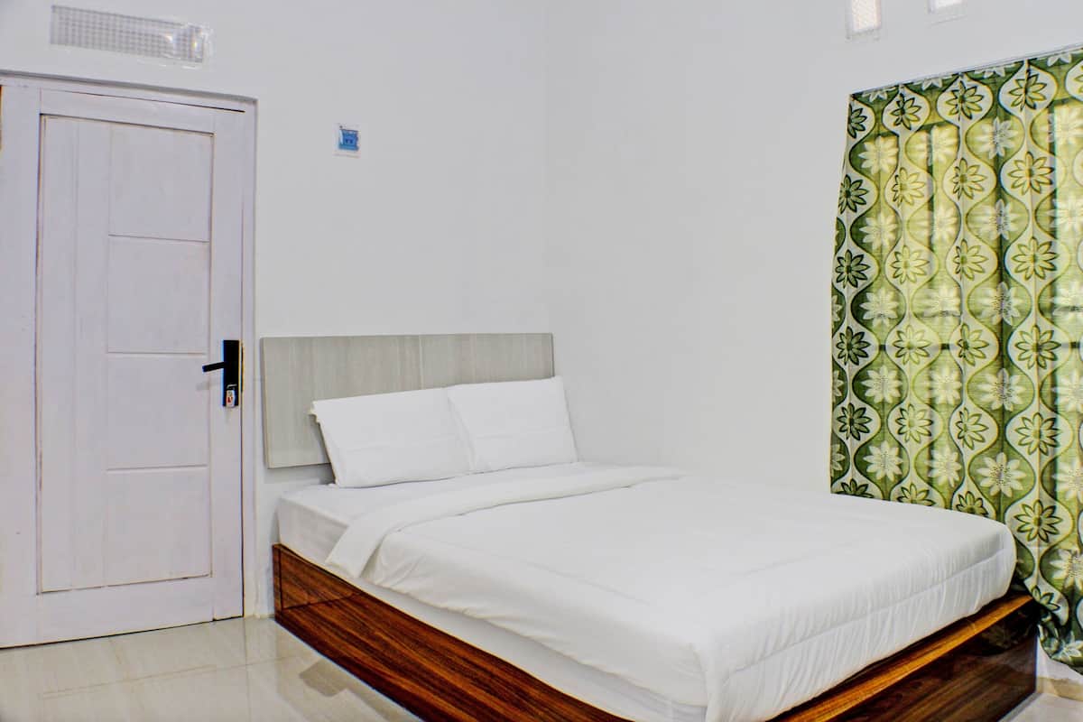 A bedroom with a wooden bed frame, white bedding, and a green patterned curtain.