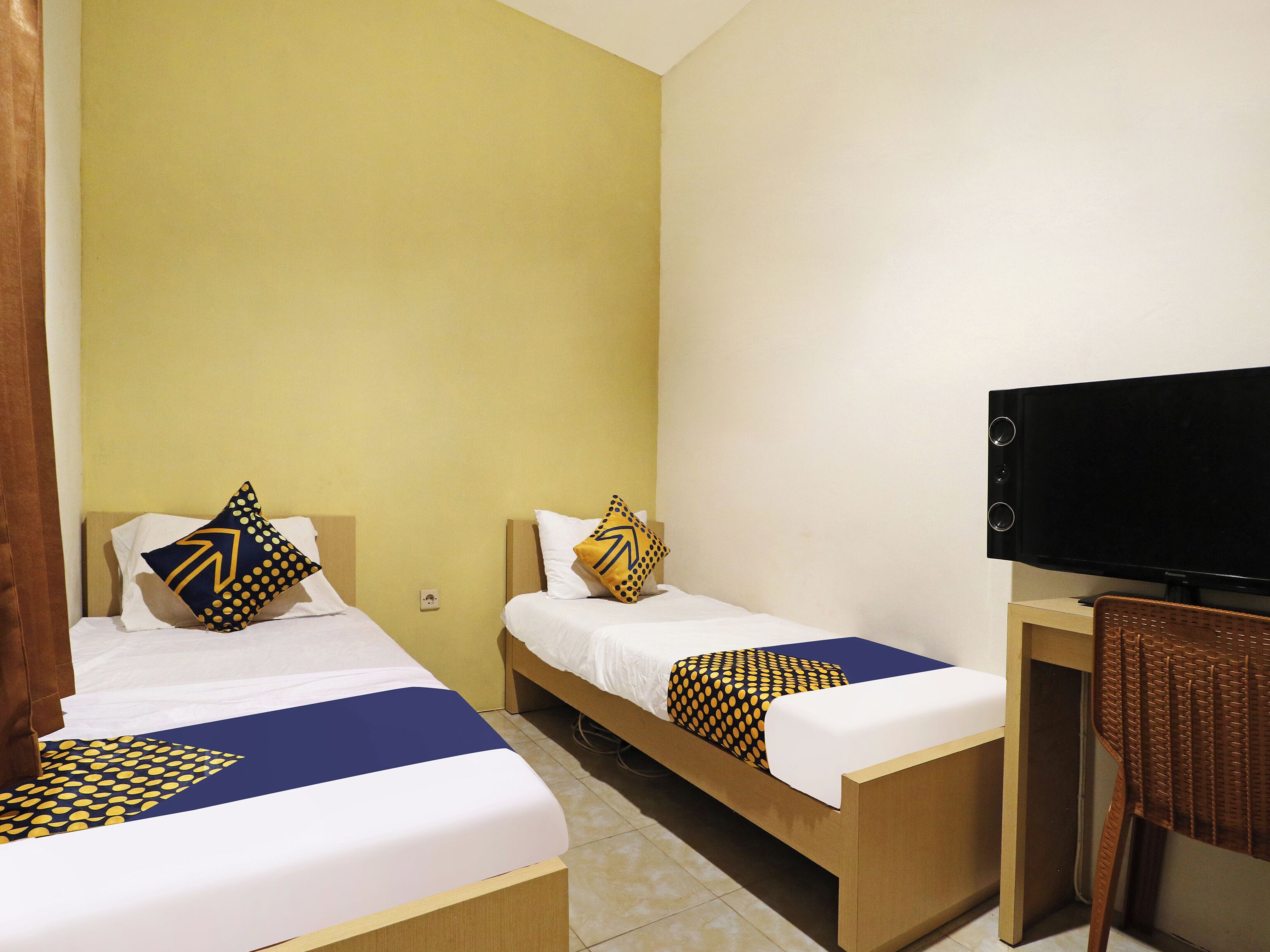 A hotel room with two beds, a television, and a desk.