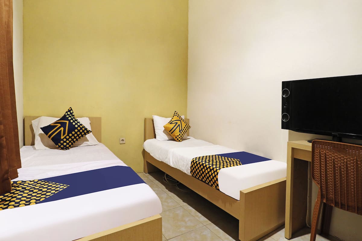 A hotel room with two beds, a television, and a desk.