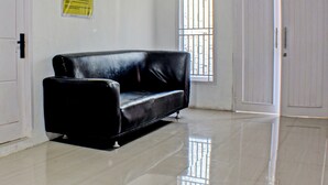 Un sofá de cuero negro en una habitación con paredes blancas y un piso brillante de baldosas.