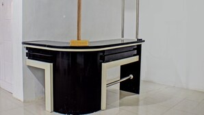 Un escritorio blanco y negro con un cajón, un estante pequeño y una barra de metal.