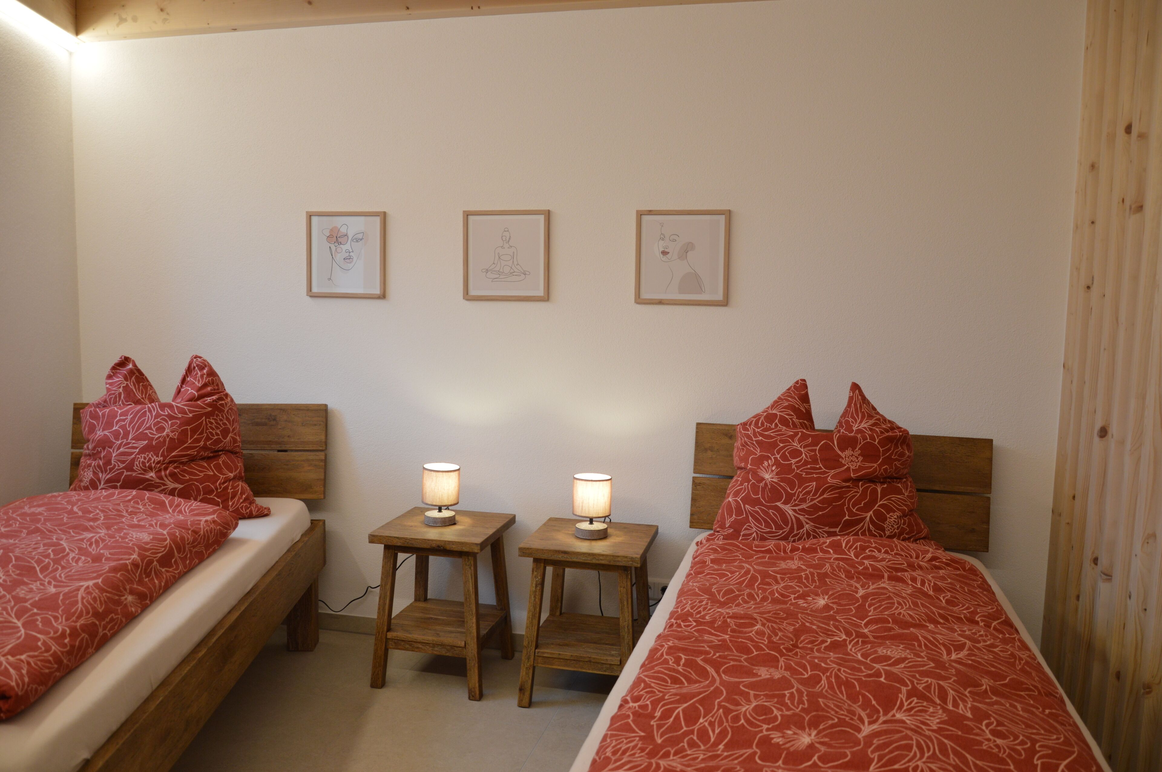 Une chambre à coucher avec deux lits simples, chacun doté d’une tête de lit en bois, d’une table de chevet avec une lampe et d’un tableau accroché au mur.