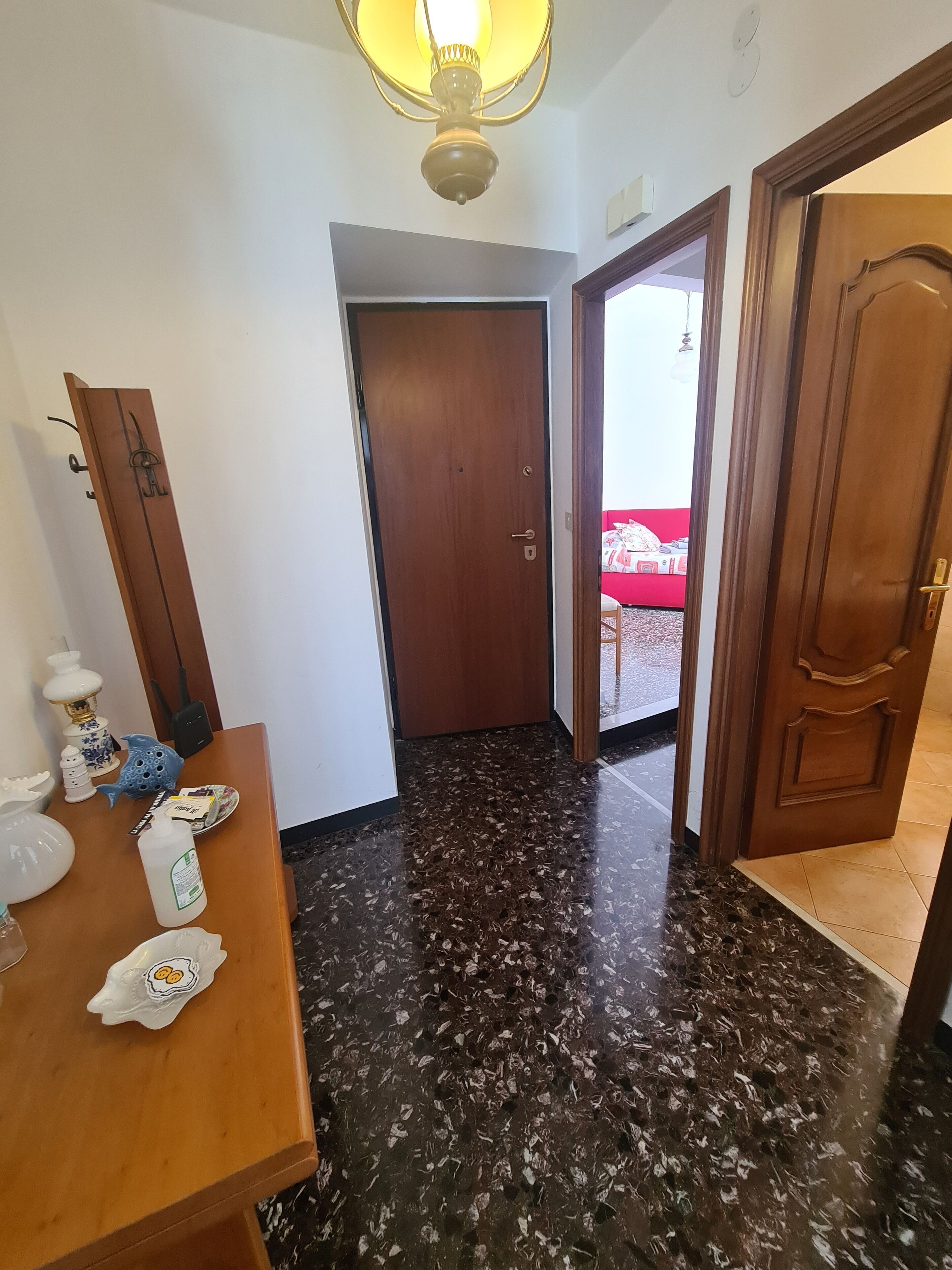 A room with a wooden door, a table with various items, and a dark speckled floor.