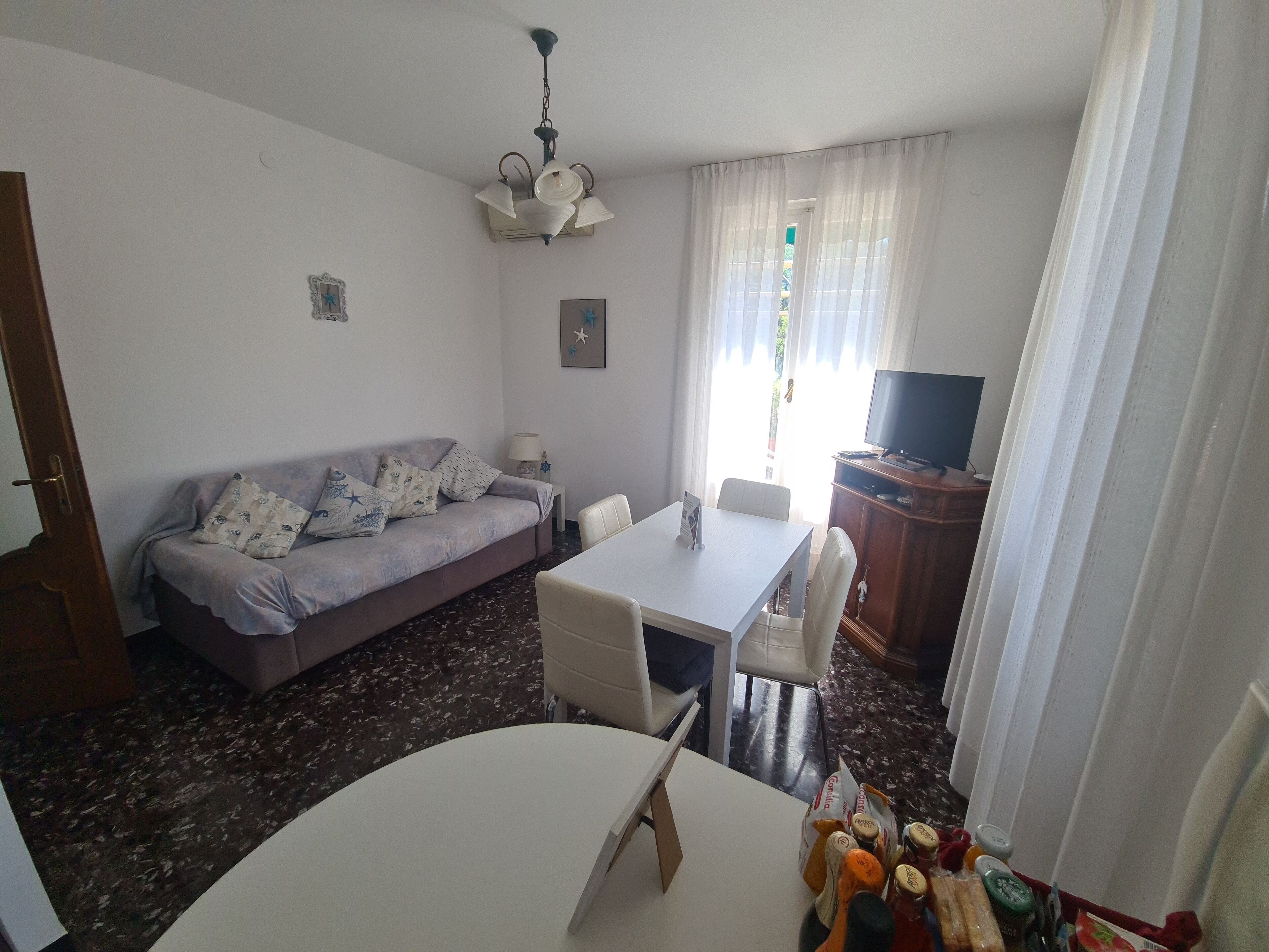 Ein Wohnzimmer mit einer Couch, einem Esstisch und einem Fernseher.