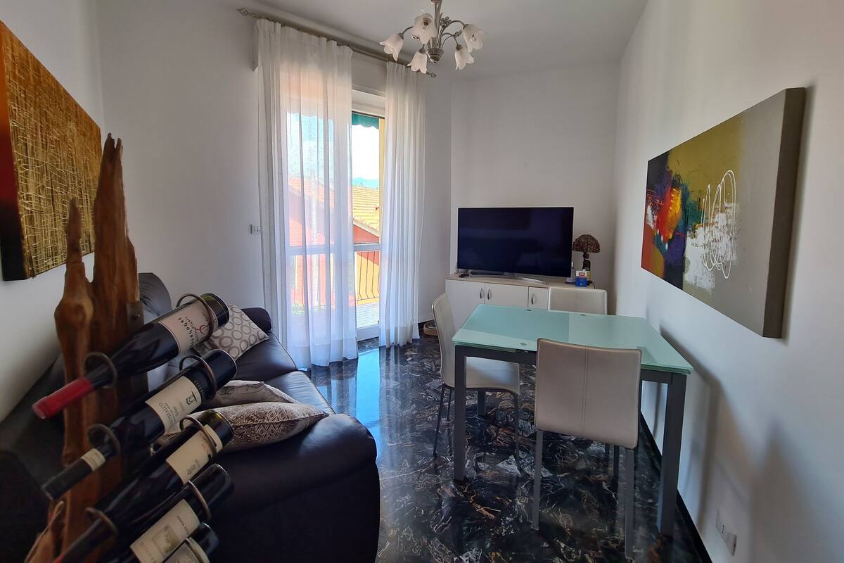 Ein modernes Wohnzimmer mit einer Couch, Fernseher, Esstisch und Kunstwerken.